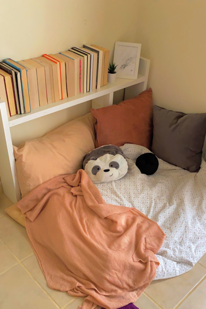 Floor reading nook with cushions and blanket setup in a small apartment