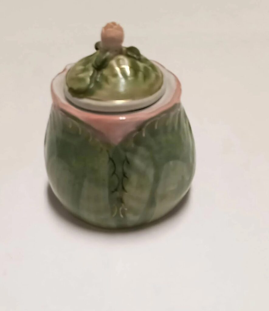 A vintage-style matte green ceramic lidded cabbage tureen or sugar bowl shot against a clean white background.